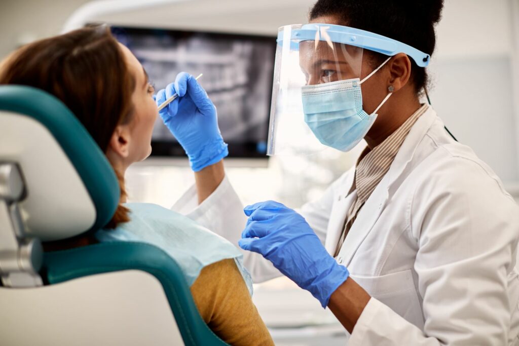 black female dentist examining woman s teeth durin 2023 02 02 18 50 00 utc 1
